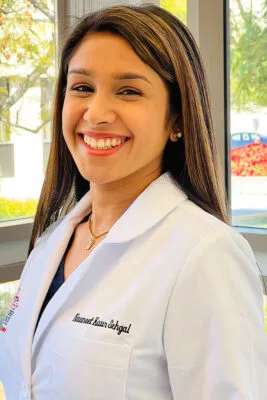 Portrait of Dr. Sehgal smiling in a white labcoat. 
