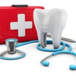 3D tooth model with stethoscope and dental mirror beside a red first aid kit, representing emergency dental care